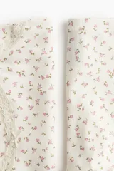 Conjunto de pijama de dos piezas en punto acanalado color blanco con estampado de pequeñas flores rosas. El top es de breteles finos con ribete de encaje en el escote y bajo sobrehilado. El short tiene cintura elástica y bajo sobrehilado.