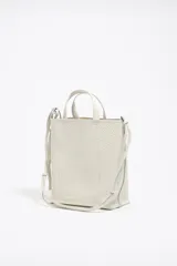 Bolso de mano mediano marca Bimba y Lola, color naranja, confeccionado en cuero con textura granulada. Tiene doble asa corta, correa bandolera ajustable y extraíble, logo estampado en el frente y herrajes plateados. El interior cuenta con etiqueta de tejido con el logo de la marca.