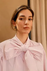 Camisa de algodón a rayas verticales rosas y blancas, con cuello alto y lazo grande en el cuello.