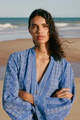 Camisa azul con bordados blancos, de cuello redondo con escote pico y manga larga.