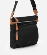 Bandolera negra de poliéster con detalles en cuero sintético color marrón. Tiene correa transversal ajustable, cierre de cremallera, bolsillos delanteros y placa metálica con el logo de la marca.