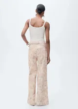 Pantalón de jean de corte wide leg con estampado floral en tonos pastel. Tiene tiro alto, cinco bolsillos, trabillas y cierre frontal con cremallera y botón.