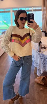 Sweater tejido en lana color crema con apliques de cuero bordados a mano en forma de chevron en tonos marrón, amarillo y rosa.