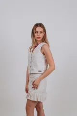 Chaleco blanco con bordado floral en dorado, con cuello en V y cierre frontal con botones.