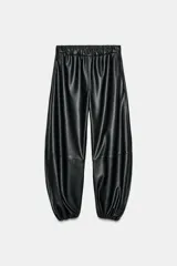 Pantalón bombacho negro de tiro medio, confeccionado en tejido efecto piel, con cintura elástica, bolsillos laterales ocultos y bajo abullonado con elástico.