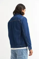 Campera de jean celeste de corte clásico, con cuello camisero, cierre frontal con botones metálicos negros, bolsillos con solapa abotonada en el pecho y bolsillos laterales.