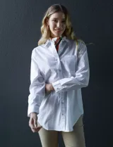 Camisa blanca de manga larga, corte holgado, con cuello con solapa, abertura central con botones y bolsillo aplicado en el pecho.