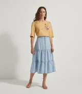 Pollera midi de liocel celeste, con corte evasé y tres niveles de volantes. Presenta abotonadura frontal completa y ruedo desflecado.