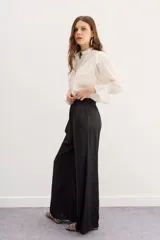 Pantalón palazzo negro de tiro alto con cintura elastizada y bolsillos diagonales.