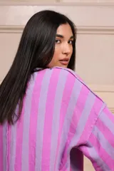 Buzo de manga 3/4 con bolsillo. Estampado a rayas verticales lilas y violetas con terminaciones desflecadas.