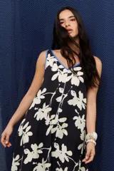 Vestido largo negro con estampado floral blanco, escote en V y corte holgado.