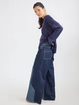 Pantalón ancho de denim con diseño patchwork en diferentes tonos de azul, con tiro alto, corte holgado y cierre frontal con botones.