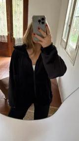 Campera negra oversize de tela tipo plush con cierre frontal y capucha.
