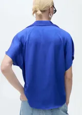 Camisa color crema de manga corta con tejido satinado, corte regular, cuello camisero y cierre delantero con botones.