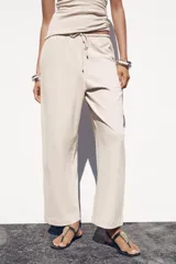 Pantalón ancho color beige, de tiro medio y cintura ajustable con cordones.