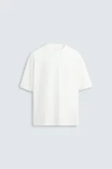 Camiseta color crudo de corte holgado, confeccionada en tejido de algodón pesado. Tiene cuello redondo y mangas cortas sin costura de sisa.
