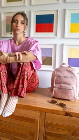 Mochila rosa de tafeta con doble apertura superior con cierre y tiradores metálicos. Incluye bolsillos internos, tres bolsillos con cierre metálico al frente y uno posterior. Asa corta de mano y correas para la espalda regulables.