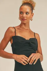 Vestido corto negro ajustado al cuerpo, con tirantes finos regulables y detalle de moño en el busto.