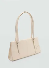 Bolso tipo tote de color crema, con efecto piel, forro interior, asa corta y asa de hombro. Tiene cierre a presión y cierre de cremallera, bolsillo interior y hebillas decorativas.
