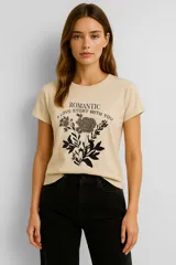 Remera color crema de algodón, de manga corta y cuello redondo, con estampado de una rosa y texto en color negro.