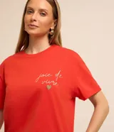 Remera roja de algodón con mangas cortas y cuello redondo. Presenta un bordado con la frase "joie de vivre" y un corazón de strass en el pecho.