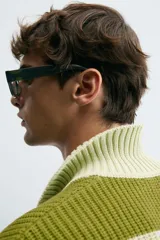 Sweater de punto a rayas horizontales anchas color verde oliva y verde claro, con cuello polo y mangas largas. Tejido en hilatura con algodón y lino, con terminaciones en rib.