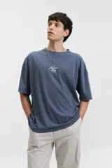 Remera azul de manga corta con cuello redondo, corte holgado y logo bordado en el pecho.