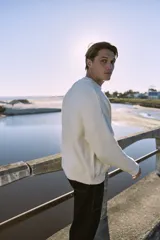 Sweater blanco de tejido plano, con cuello redondo, corte oversize y hombros caídos.