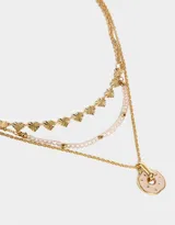 Collar corto dorado de tres capas: una con mostacillas doradas, otra con dijes de corazones y otra con dije circular rosa.