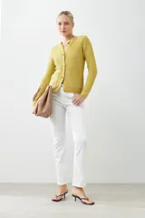 Chaqueta tejida color amarillo con botones metálicos y bolsillos frontales.
