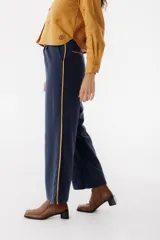 Pantalón de vestir color marrón con corte recto y cintura alta. Presenta una fina cinta roja a modo de cinturón.