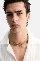 Camisa blanca de corte relaxed fit confeccionada en tejido de algodón y lino. Tiene cuello bowling, manga larga con puños abotonados, jaretas en el delantero, bolsillos de parche en pecho y cadera, bajo con aberturas laterales y cierre frontal con botones.