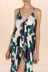 Vestido playero estampado con flores moradas y verdes, breteles finos y volados en el frente.