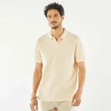 Remera tipo polo color crema, de piqué de algodón, con cuello clásico, tapeta de dos botones y mangas cortas con ribete.