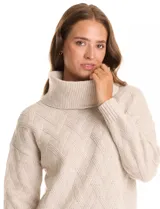 Buzo de punto grueso color beige, con cuello volcado y textura en relieve. Tiene mangas largas de corte hombro caído y puños anchos.