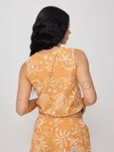 Top corto negro con estampado de flores y figuras geométricas en color crema, con breteles anchos y lazo ajustable en la cintura.