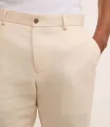 Conjunto de saco y pantalón color beige, confeccionado en lino y viscosa. El saco es de corte clásico con solapas y cierre de dos botones. El pantalón es de corte relajado con cintura con trabillas y bolsillos laterales.