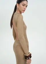 Vestido largo de tejido de punto de canalé color dorado con lúrex. Tiene espalda abierta, cuello perkins, mangas largas y cierre de botones en la parte posterior del cuello.