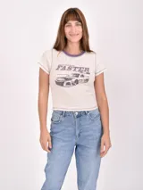 Remera blanca de corte cropped con cuello redondo y mangas cortas. Estampado frontal con un auto de carreras y la palabra "Faster".