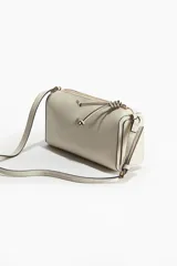 Cartera bandolera rectangular color crudo con correa ajustable y cierre superior.