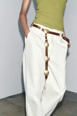 Cinturón marrón de cuero con apliques metálicos dorados en forma de círculos y corazones.