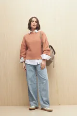 Sweater de punto color salmón con cuello redondo y mangas anchas. Presenta un diseño calado en la parte superior y tejido tramado horizontal en el resto del cuerpo.
