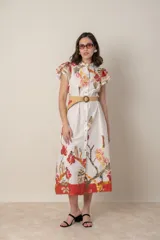 Vestido midi camisero de algodón color natural con estampado de flores, animales y ramas en tonos rojo, marrón, verde y azul. Tiene cuello mao, mangas cortas con volados, bolsillos laterales y cinturón de soga color beige.