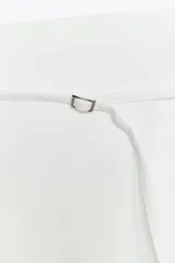 Falda pantalón blanca de tiro medio, con corte ligeramente acampanado y detalle de cinturón fino con hebilla metálica.