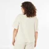 Camisa beige de manga corta con cuello clásico y cierre frontal con botones. Presenta bordados geométricos en color negro.