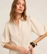 Vestido chemise evasé midi de viscolino color crema, con mangas abullonadas cortas, cuello camisero, botones delanteros, cinturón tejido para lazo en la cintura y bajo fruncido con estampa de palmeras y follaje.