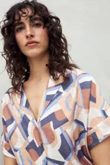 Camisa estampada de manga corta con cuello solapa y botones de nácar al frente, confeccionada en un tejido liviano de sutil textura que aporta movimiento y frescura.