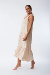 Vestido largo color beige, de corte recto, con breteles finos y volados en los hombros.