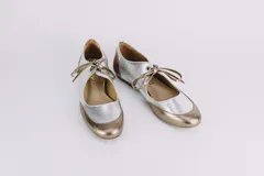 Zapatos tipo ballerina plateados con puntera y talón dorados, y tira sobre el empeine con lazo decorativo.