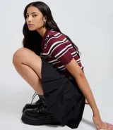 Short pollera negro de sastrería con pliegues estructurados, cintura con trabillas y cinturón ajustable con hebilla redonda.